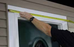 Measuring the crosshead width above the door with a tape measure